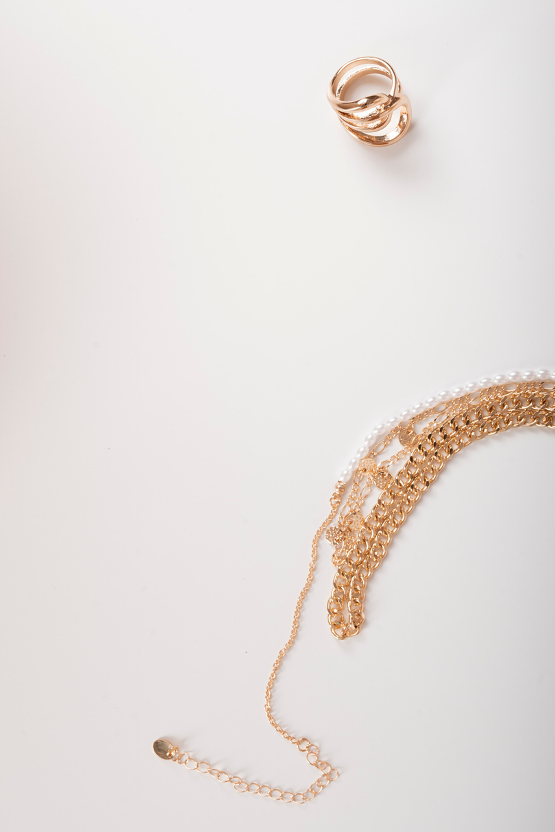 Photo of necklaces and a ring top view on white background