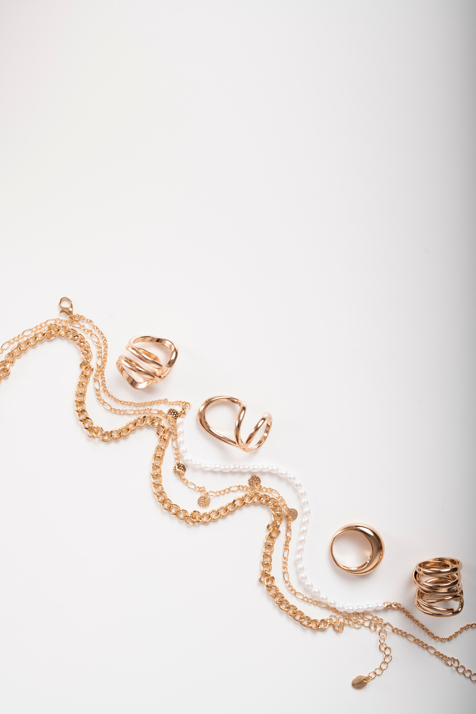 Photo of necklaces and rings top view on white background